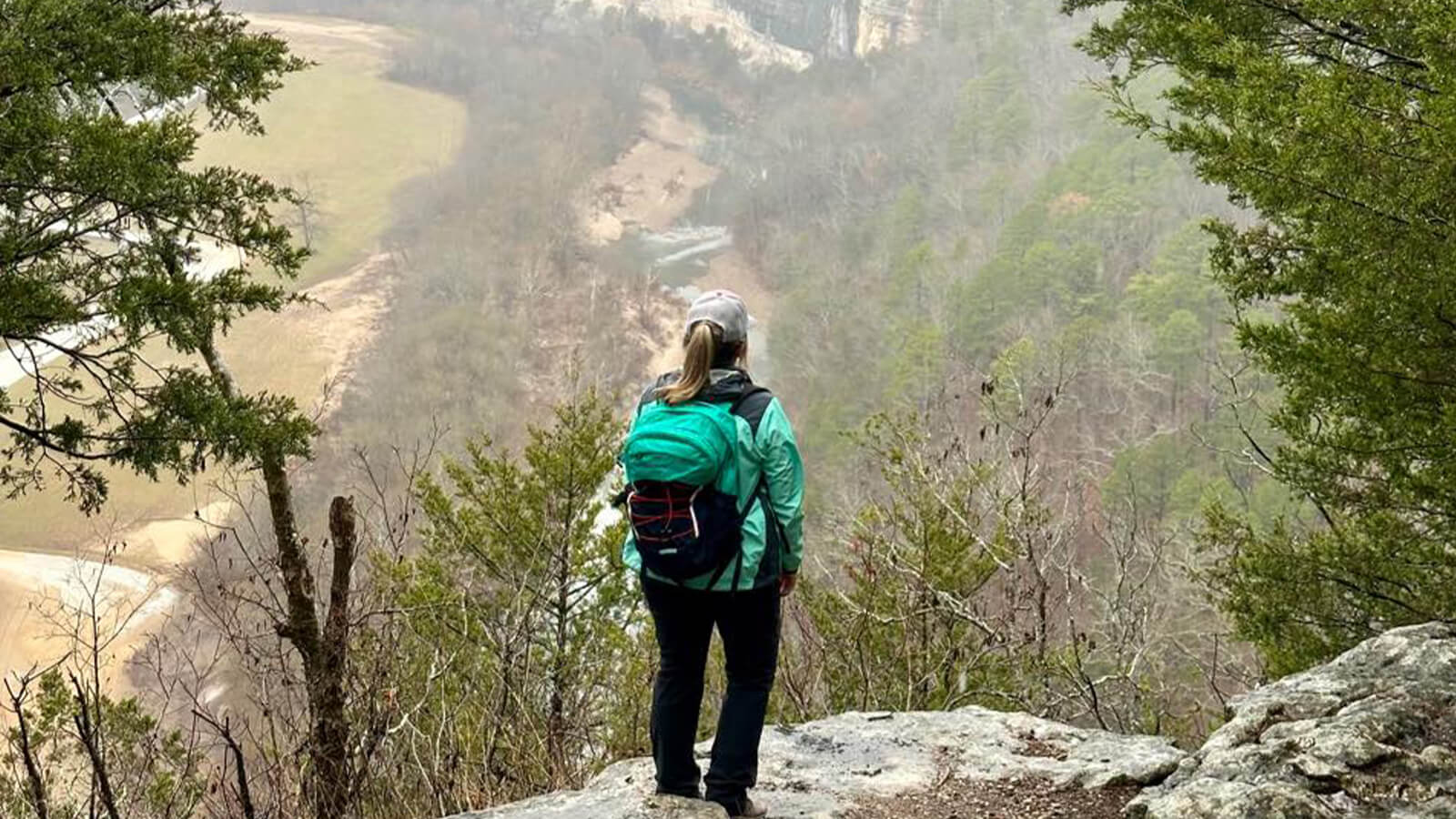 Woman overlooking the mountains from a cliff